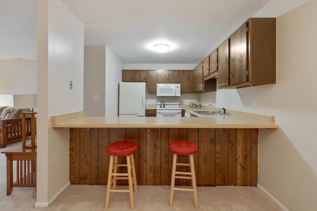 kitchen featuring light carpet, kitchen peninsula, a breakfast bar, white appliances, and sink