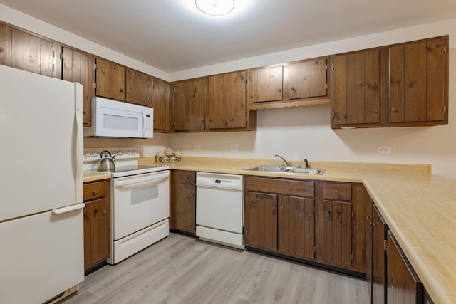 kitchen with light hardwood / wood-style floors, white appliances, and sink