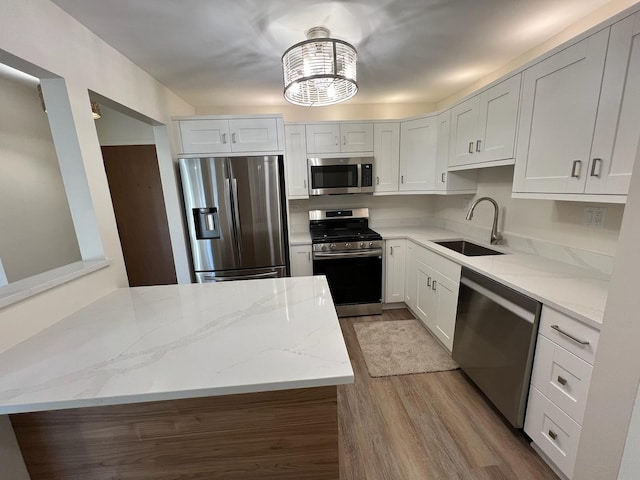 kitchen with light stone countertops, light hardwood / wood-style flooring, white cabinets, and appliances with stainless steel finishes