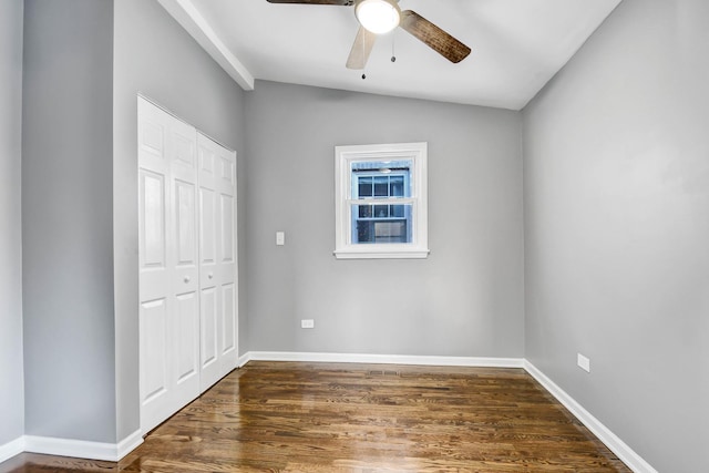 unfurnished bedroom with ceiling fan, dark hardwood / wood-style floors, vaulted ceiling, and a closet