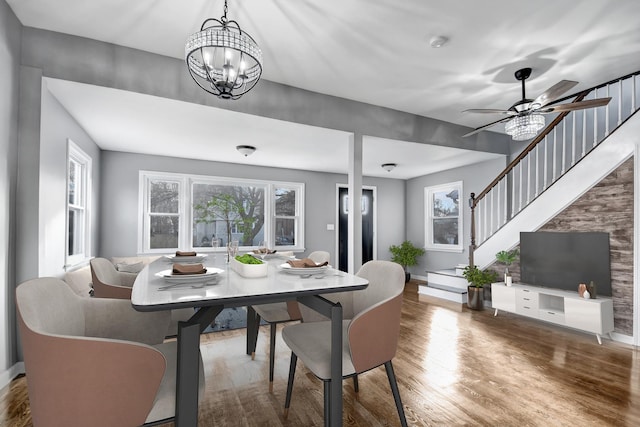 dining area featuring ceiling fan with notable chandelier and dark wood-type flooring