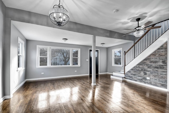 unfurnished living room featuring ceiling fan with notable chandelier and dark wood-type flooring