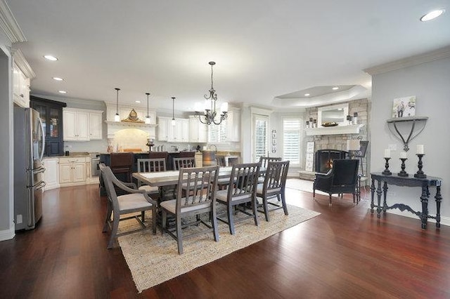 dining room with a fireplace, dark wood-type flooring, a chandelier, and crown molding