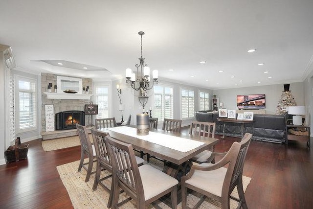 dining space with a fireplace, a chandelier, dark hardwood / wood-style floors, and ornamental molding