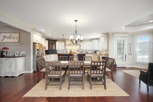 dining space with ornamental molding, dark wood-type flooring, and an inviting chandelier