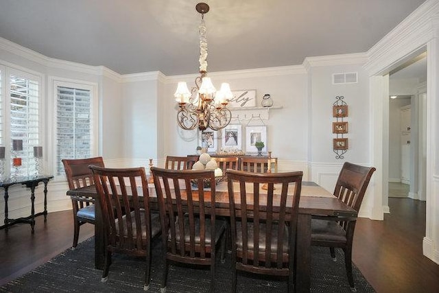 dining area featuring dark hardwood / wood-style flooring, ornamental molding, and an inviting chandelier