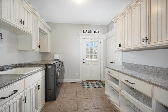 laundry area featuring cabinets, light tile patterned flooring, washing machine and dryer, and sink