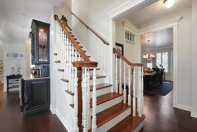 stairway with hardwood / wood-style floors and an inviting chandelier