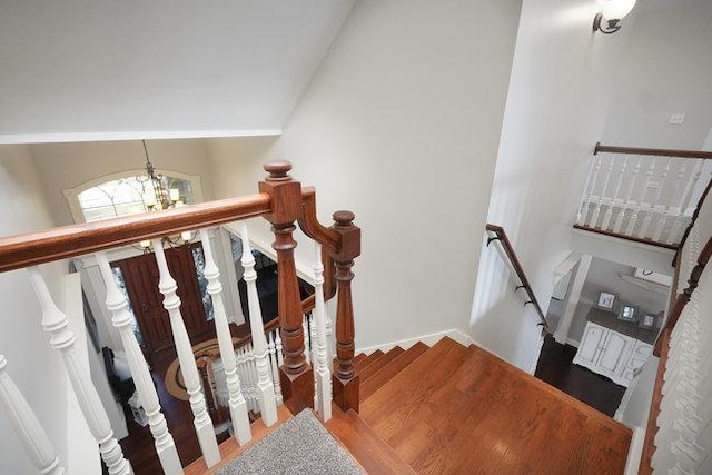 stairway featuring a chandelier, wood-type flooring, and vaulted ceiling