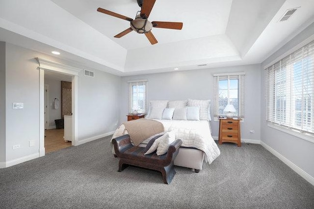 carpeted bedroom featuring a tray ceiling and ceiling fan