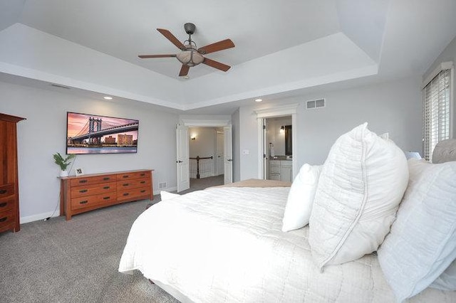 carpeted bedroom featuring connected bathroom, a raised ceiling, and ceiling fan