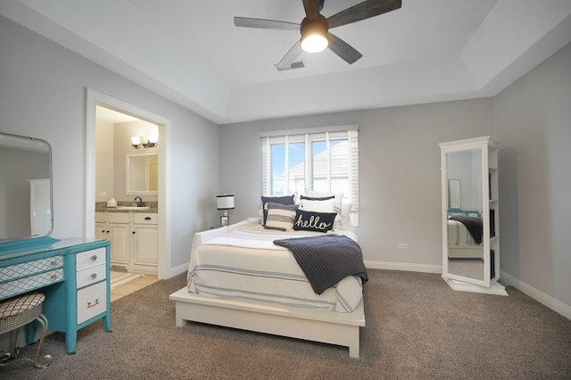 bedroom featuring a raised ceiling, ceiling fan, carpet floors, and ensuite bathroom