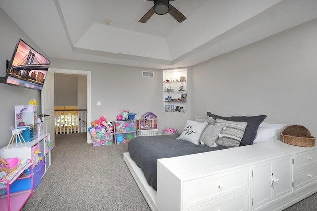 carpeted bedroom with a tray ceiling and ceiling fan