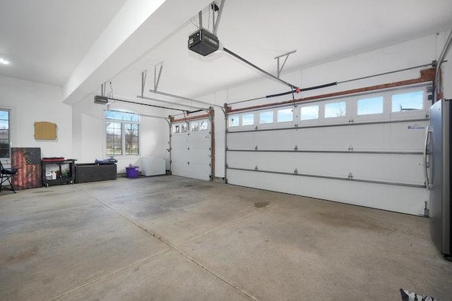 garage with stainless steel fridge and a garage door opener