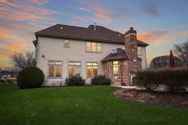 back house at dusk featuring a yard