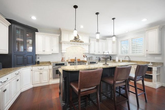 kitchen featuring a breakfast bar, oven, hanging light fixtures, a kitchen island, and white cabinetry