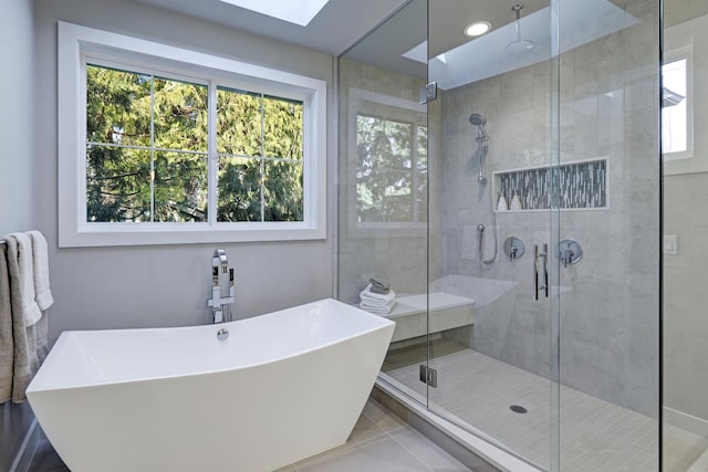 bathroom with tile patterned flooring, shower with separate bathtub, a skylight, and a wealth of natural light