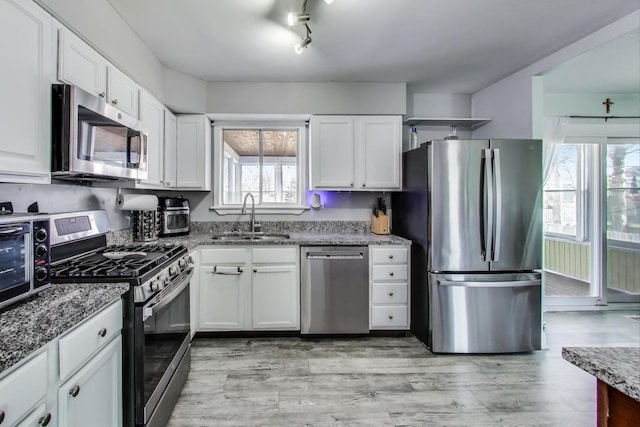 kitchen with sink, stainless steel appliances, stone counters, and white cabinets