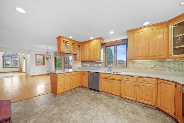 kitchen with sink, dishwasher, an inviting chandelier, kitchen peninsula, and decorative backsplash