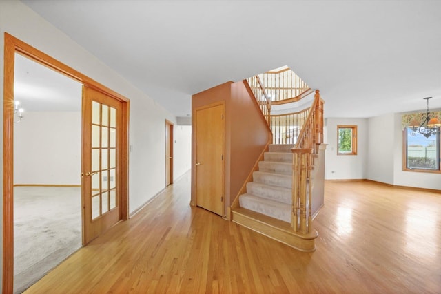 stairs featuring french doors, a chandelier, and hardwood / wood-style flooring