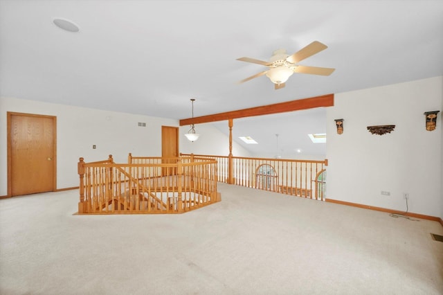 carpeted empty room with ceiling fan and lofted ceiling with skylight