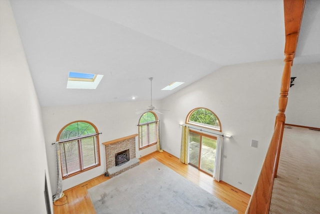 living room featuring a brick fireplace, light hardwood / wood-style floors, vaulted ceiling, and ceiling fan