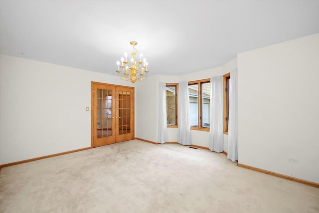 carpeted spare room with french doors and a chandelier