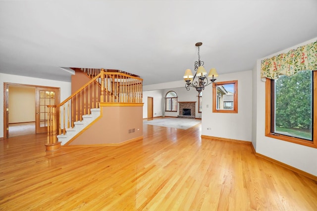 unfurnished living room featuring a fireplace, light hardwood / wood-style flooring, and a chandelier