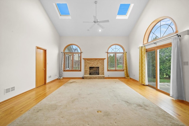 unfurnished living room with ceiling fan, light hardwood / wood-style flooring, high vaulted ceiling, and a healthy amount of sunlight