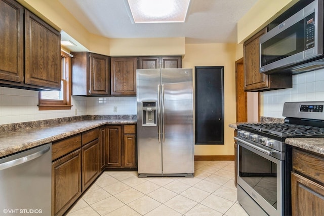 kitchen with tasteful backsplash, light tile patterned floors, and appliances with stainless steel finishes