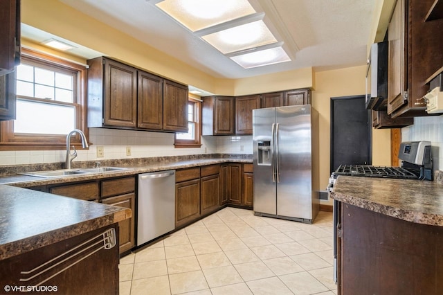 kitchen with backsplash, sink, light tile patterned floors, and appliances with stainless steel finishes