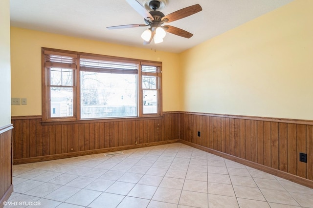 tiled empty room with ceiling fan and wooden walls