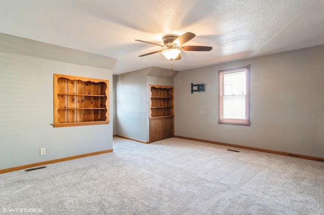 carpeted spare room featuring a textured ceiling, vaulted ceiling, and ceiling fan