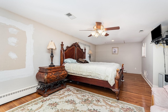 bedroom with ceiling fan, hardwood / wood-style flooring, and a baseboard heating unit