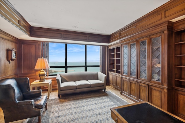 living room featuring wood walls, a water view, built in features, and ornamental molding