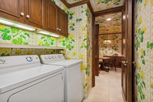 laundry room with crown molding, washer and clothes dryer, light tile patterned flooring, and cabinets