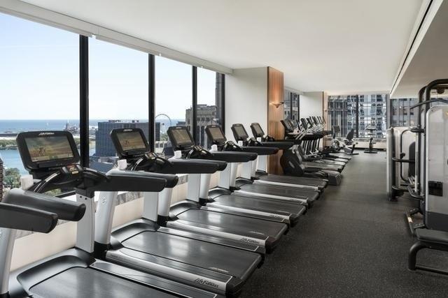 gym featuring a water view, floor to ceiling windows, and a healthy amount of sunlight