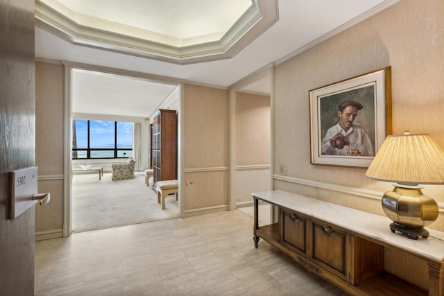 hall featuring light carpet, a raised ceiling, and ornamental molding