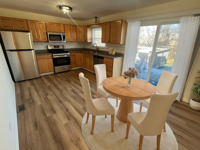 kitchen with stainless steel appliances, light hardwood / wood-style flooring, tasteful backsplash, and sink