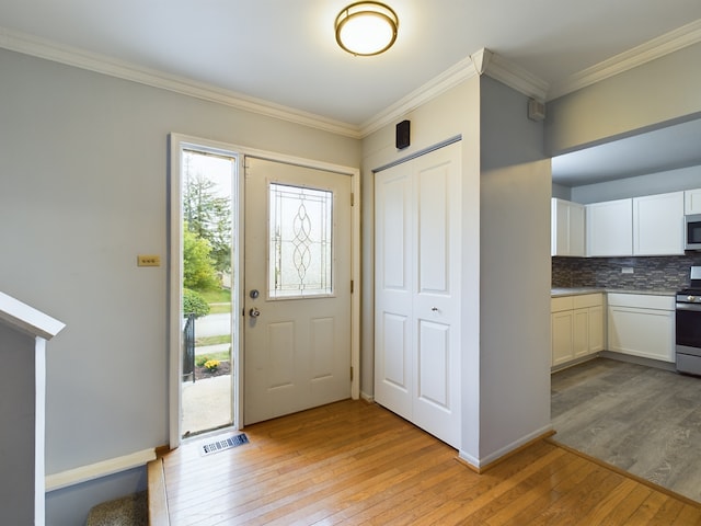 entryway featuring ornamental molding and light hardwood / wood-style flooring