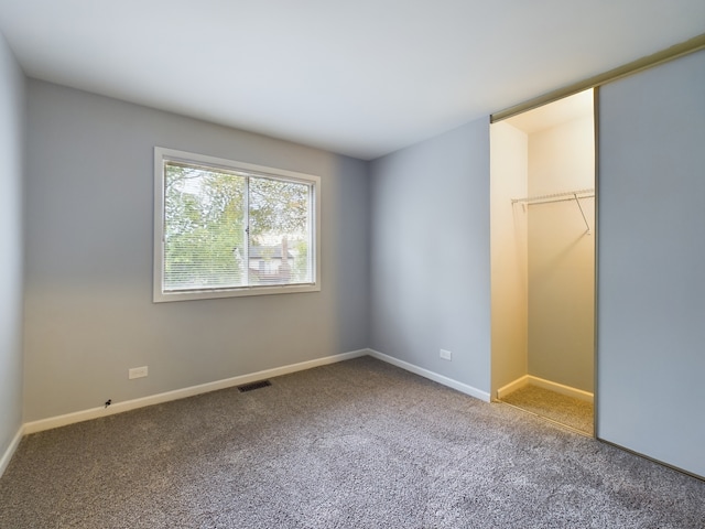 unfurnished bedroom with carpet, a walk in closet, and a closet