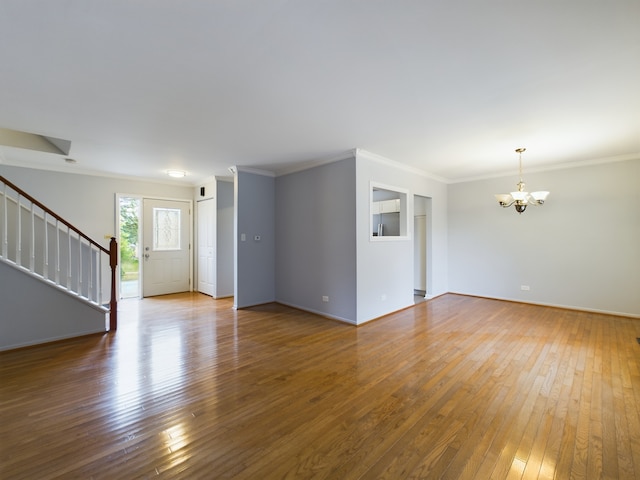 spare room featuring crown molding, a chandelier, and hardwood / wood-style flooring