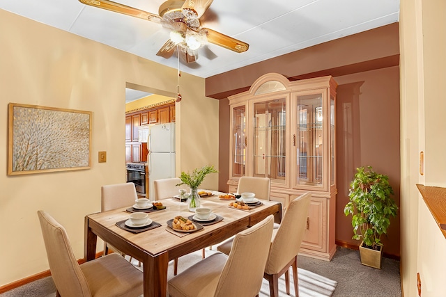 carpeted dining room with ceiling fan