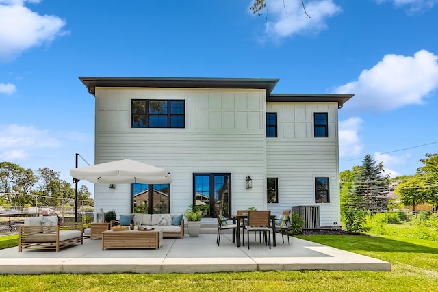 rear view of house featuring a patio, fence, an outdoor living space, a lawn, and board and batten siding