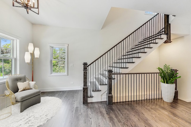 staircase featuring a towering ceiling, baseboards, a wealth of natural light, and wood finished floors