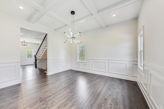 spare room with a notable chandelier, dark wood-type flooring, coffered ceiling, stairs, and beamed ceiling