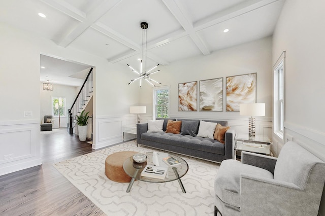 living area featuring stairway, a chandelier, a wealth of natural light, and beamed ceiling