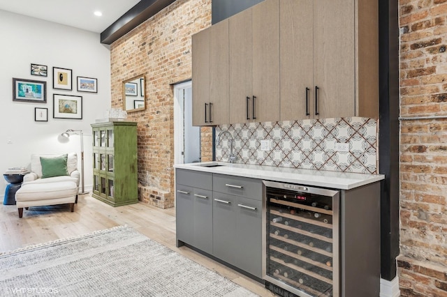 kitchen with gray cabinetry, brick wall, sink, and wine cooler