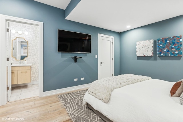 bedroom featuring ensuite bath, light hardwood / wood-style flooring, and sink