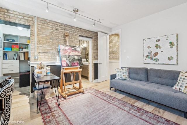 living room with rail lighting, brick wall, and light wood-type flooring